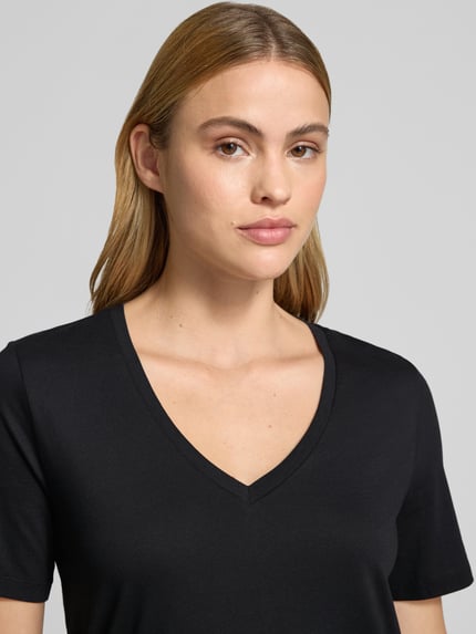Vrouwenmodel draagt Regular Fit T-Shirt aus reiner Baumwolle van Marc O'Polo in effen zwart, V-hals, korte mouw, puur katoen, close-up bovenlichaam.
