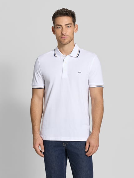 Męski model nosi Regular Fit Poloshirt mit Kontraststreifen von Christian Berg Men, biała bawełna, krótki rękaw, guziki, krój regular fit, widok całej sylwetki z przodu.
