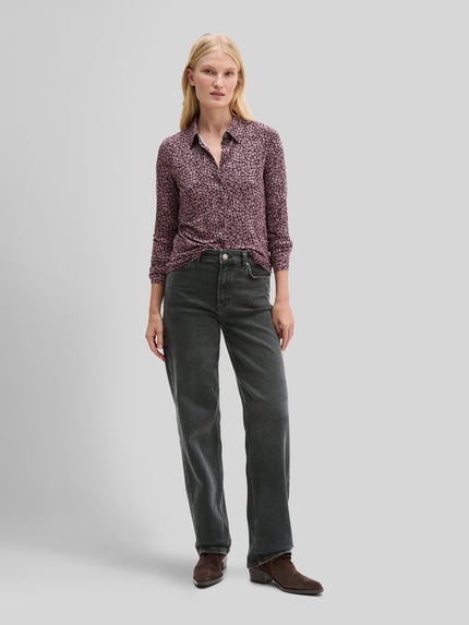 Frauenmodel trägt Longline Langarmbluse mit Label-Detail von Marc O'Polo, abstraktes grafisches Muster, Allover-Optik, Ganzkörperansicht von vorne.
