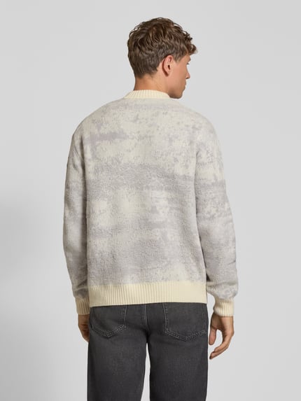 Männermodel trägt Pullover mit geripptem Rundhals Modell 'Kastet' von BOSS Orange, marmoriertes Allover-Muster in Strickoptik, Ganzkörperansicht Rückansicht.