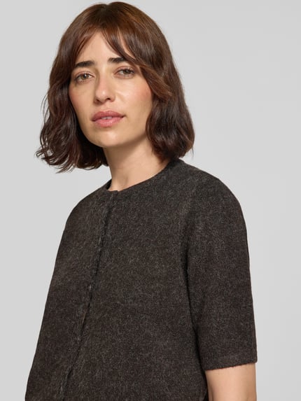 Frauenmodel trägt Regular Fit Strickjacke mit kurzem Arm Modell 'VMDOFFY' von VERO MODA in dunklem Braunton, Nahaufnahme Oberkörper.