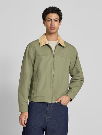 Männermodel trägt Regular Fit Blouson aus reiner Baumwolle von Tommy Jeans in Optik: Unifarben mit Umlegekragen, Ganzkörperansicht von vorne.