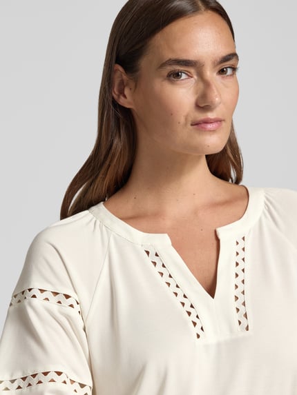 Frauenmodel trägt Relaxed Fit T-Shirt aus Modal-Mix von s.Oliver BLACK LABEL in Creme mit geometrischen Aussparungen, Nahaufnahme Oberkörper. Damen T-Shirt.