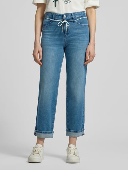 Vrouwenmodel draagt Straight Fit Jeans met fixierte pijpboorden van Marc Cain uit elastische katoenmix in blue denim, gulp- en achterzakken, knoop- en ritssluiting, bandwijdte maat 36: 39 cm, binnenbeenlengte maat 36: 71 cm, frontale opname volledige lichaamslengte.