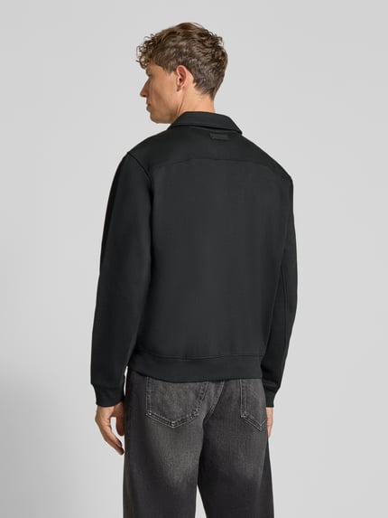Männermodel trägt Regular Fit Sweatjacke aus elastischem Baumwoll-Mix von GUESS in Schwarz mit Umlegekragen und Label-Detail, Ganzkörperansicht Rückansicht