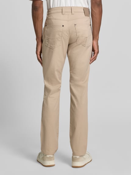 Męski model nosi Regular Fit Hose mit Eingrifftaschen Modell 'CORDOBA' von bugatti, mieszanka bawełny i elastanu, krój regular fit, szerokość w rozmiarze 32/32: 38 cm, długość wewnętrzna nogawki w rozmiarze 32/32: 82 cm, jasny beż, klasyczne kieszenie, gładka faktura, pełny widok z tyłu.