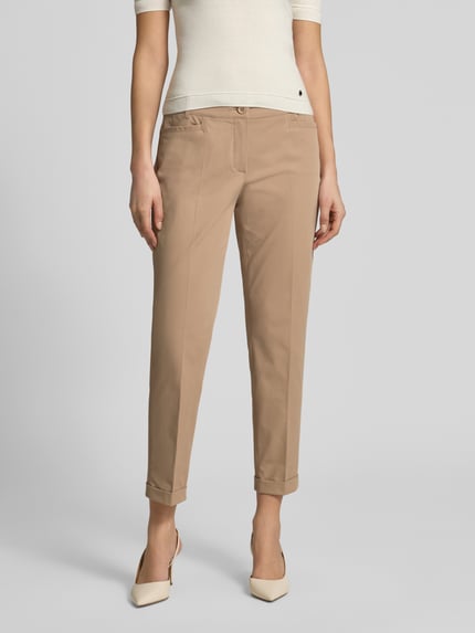Vrouwenmodel draagt dames chino uit tech-materiaal met katoenmix, straight fit, persplooien, model 'UTE' van Raffaello Rossi, verkorte pasvorm, knoop- en ritssluiting, steek- en achterzakken, vaste omslag aan de pijpen, riemlussen, bandwijdte maat 36: 40 cm, binnenbeenlengte maat 36: 68 cm. Volledige lichaamsaanzicht van voren.