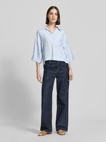 Frauenmodel trägt Bluse mit Brusttasche und V-Ausschnitt Modell 'Felmara' von OPUS, hellblau, Modal-Mix, Loose-Fit, Ganzkörperansicht von vorne.