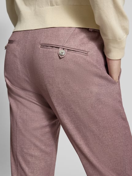 Frauenmodel trägt rosafarbene Hose aus Material-Mix mit dezentem Glanz, Produktfoto von Slim Fit 2-Knopf-Sakko mit Pattentaschen von Zuitable, Baumwoll-Lyocell-Anteil, Nahaufnahme Rückenansicht.