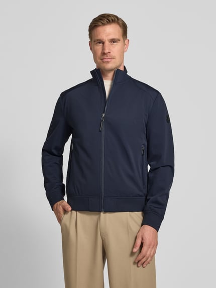 Männermodel trägt dunkelblaue Jacke mit Stehkragen und Reißverschlusstaschen Modell 'Pablo' von JOOP! Collection, Regular-Fit, Material-Mix mit Stretch-Anteil, Ganzkörperansicht von vorne.