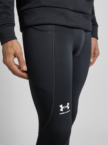 Männermodel trägt Leggings mit elastischem Bund und Logo von Under Armour in Schwarz, körpernahe Passform, Nahaufnahme Oberschenkel.