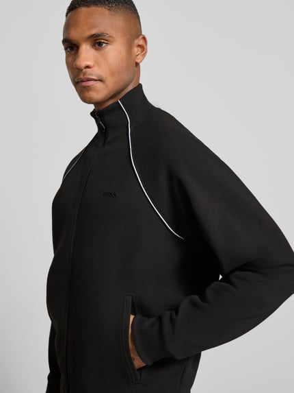 Männermodel trägt Regular Fit Sweatjacke aus Baumwoll-Mix von BOSS Green in Two-Tone-Optik mit Kontraststreifen, seitliche Eingrifftaschen, Nahaufnahme Oberkörper.