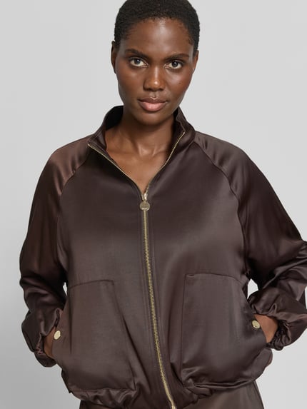 Frauenmodel trägt Regular Fit Blouson aus Viskose-Mix von s.Oliver BLACK LABEL, dunkelbrauner Satin-Look, glatte Textur, Nahaufnahme Oberkörper, Damen Bomberjacke / Blouson von s.Oliver BLACK LABEL.