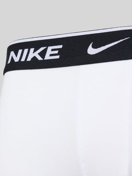 Männermodel trägt weiße Trunks aus Baumwoll-Mix Modell 'ESSENTIAL' von Nike mit elastischem Logo-Bund, Nahaufnahme Oberkörper.