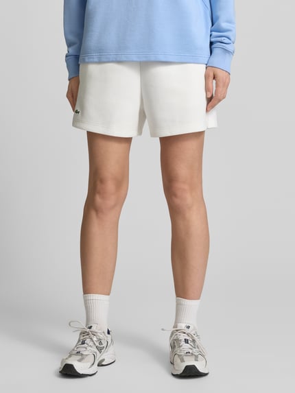 Frauenmodel trägt Regular Fit Sweatshorts aus reiner Baumwolle von Lacoste, Optik: Unifarben, Logo-Stitching, Tunnelzug, Bundabschluss: elastisch, Material: Reine Baumwolle, Ganzkörperansicht von vorne.