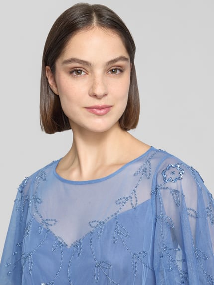 Vrouwenmodel draagt Regular Fit avondjurk met florale all-over stitching van Adrianna Papell, semi-transparant, met siersteentjes, jurk met korte mouwen, kleur blauw, detailopname bovenlichaam. Ruglengte maat 36: 145 cm, borstwijdte maat 36: 41 cm, mouwlengte maat 36: 27 cm.