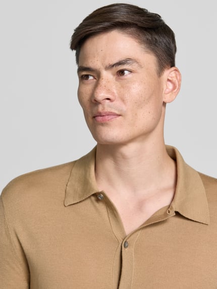 Męski model nosi Regular Fit Strickjacke aus Wolle Modell 'Verklin' von Tiger Of Sweden, kołnierzyk typu kent, listwa guzikowa, beżowa, krój regular fit, czysta wełna, długość tyłu 71 cm, długość rękawów 65 cm, zbliżenie na górną część ciała.