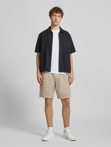 Männermodel trägt Regular Fit Sweatshorts mit Logo-Stitching von Pegador, Baumwoll-Mix, elastischer Bund, beige, Ganzkörperansicht von vorne.