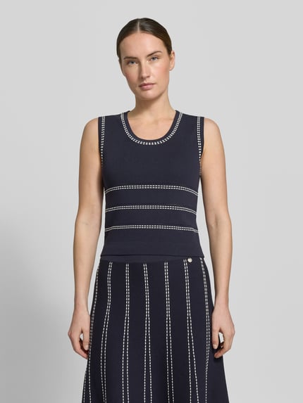 Kobiece model prezentuje top z dzianiny z mieszanki wiskozy z okrągłym dekoltem Liu Jo White, krój slim fit, hafty, długość tyłu w rozmiarze S: 47 cm, widok całej sylwetki z przodu