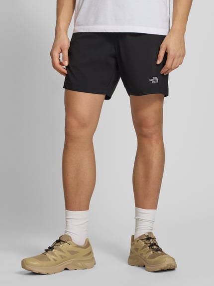 Mannenmodel draagt Regular Fit Shorts met steekzakken van The North Face in zwart met elastische tailleband, halflange pijpen, vooraanzicht close-up.