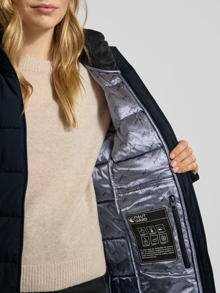 Frauenmodel trägt Steppmantel mit Sorona® Aura Filling von NAUTGÅRD, wasserabweisend, isolierend, Nahaufnahme Oberkörper.