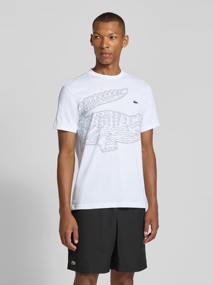 Männermodel trägt weißes Regular Fit Sport-T-Shirt aus Baumwoll-Mix von Lacoste, schwarzes Krokodil-Motiv, Herren Sport-T-Shirt, Ganzkörperansicht von vorne.