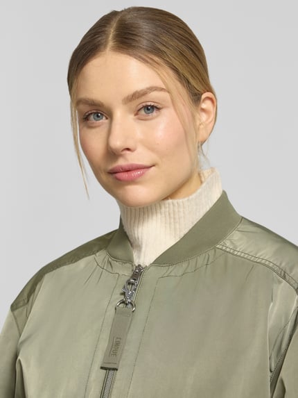 Frauenmodel trägt Jacke mit Pattentaschen Modell 'CIBLOUMINA' von CINQUE in Olivgrün, glatte Textur, Nahaufnahme Oberkörper, Regular Fit, Stehkragen, Reißverschluss.