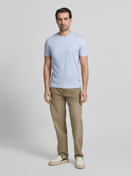 Männermodel trägt Regular Fit T-Shirt aus reiner Baumwolle Modell 'THOMPSON' von BOSS in Hellblau, unifarben, mit Label Print, Rundhals, Ganzkörperansicht von vorne.