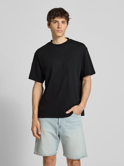 Männermodel trägt T-Shirt mit Rundhalsausschnitt Modell 'EURBAN EDGE' von Jack & Jones in Schwarz, Baumwolle, Modern Fit, Ganzkörperansicht von vorne
