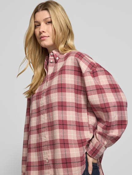 Frauenmodel trägt Langarmbluse mit Button-Down-Kragen von BOSS Orange in mehrfarbig kariertem Allover-Muster aus Webware, Nahaufnahme Oberkörper.