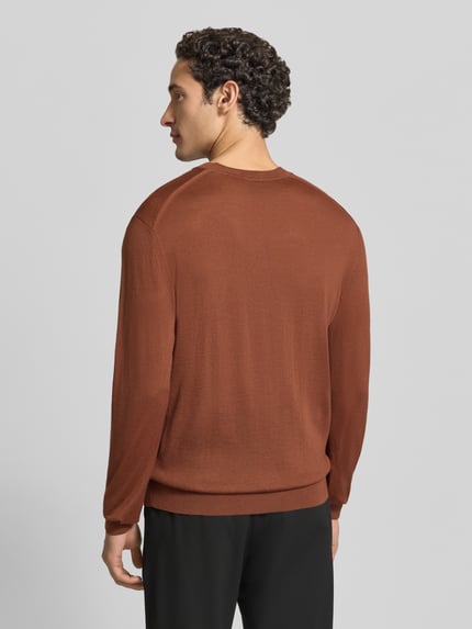 Männermodel trägt Pullover aus Wolle mit Logo-Stitching von BOSS in Braun, Feinstrick, unifarben, Ganzkörperansicht Rückansicht.