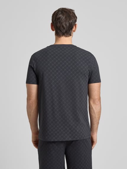 Męski model nosi T-Shirt mit Logo-Muster und Rundhalsausschnitt von JOOP! Collection, bawełna z elastanem, krój regular fit, wzór logo, grafitowy, długość tyłu w rozmiarze M 68 cm, widok całej sylwetki z tyłu.