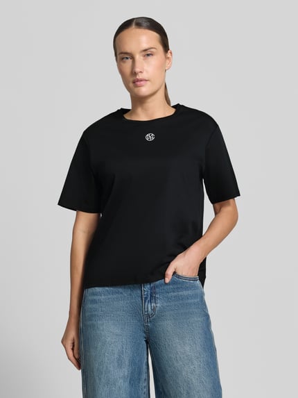 Frauenmodel trägt Regular Fit T-Shirt aus reiner Baumwolle Modell 'Melea' von MSCH Copenhagen, schwarz, Logo-Print, Nahaufnahme Oberkörper. Damen T-Shirt, Rundhalsausschnitt, Rückenlänge bei Größe XS/S 57 cm.