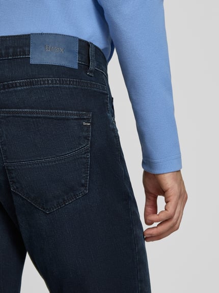 Männermodel trägt dunkelblaue Straight Fit Jeans aus Baumwoll-Mix Modell 'Cadiz' von Brax, grobe Struktur, Nahaufnahme Rückansicht, Herren Straight Fit Jeans von Brax.