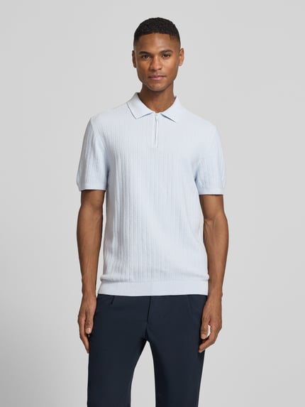 Męski model nosi Poloshirt mit kurzem Reißverschluss und Polokragen von MCNEAL, jasnoniebieski, czysta bawełna organiczna, krój body fit, prążkowane wykończenia, przód, całkowite ujęcie sylwetki.