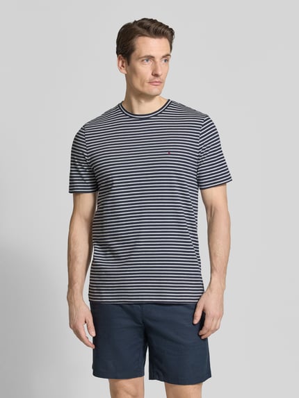 Männermodel trägt Regular Fit T-Shirt aus reiner Baumwolle von Tommy Hilfiger, gestreift, Logo-Stitching, Rundhals, Ganzkörperansicht von vorne.