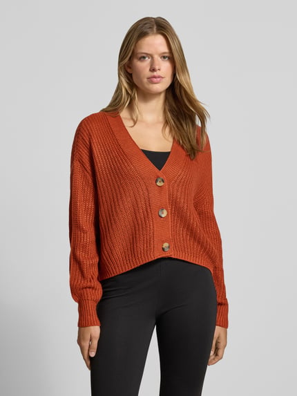Frauenmodel trägt Boxy Fit Strickjacke mit V-Ausschnitt Modell 'CAROL' von ONLY in Rostorange, grob gestrickt, Ganzkörperansicht von vorne, Damen Strickjacke von ONLY.