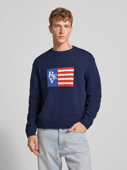 Männermodel trägt Regular Fit Strickpullover aus Baumwoll-Mix von REVIEW in Dunkelblau mit Motiv-Stitching, Nahaufnahme Oberkörper.