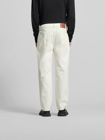 Mannenmodel draagt Regular Fit Jeans mit Knopfverschluss van Officine Générale, witte katoenen jeans met 5-pocket-design, riemlussen, knoop- en ritssluiting, volledig van achteren gezien.