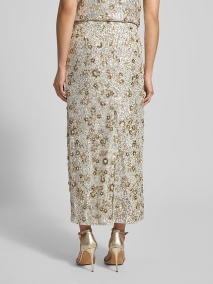 Frauenmodel trägt High Waist Maxirock mit Pailletten Modell 'Magnolia' von MSCH Copenhagen in Beige-Gold, gerader Schnitt, Material-Mix, Ganzkörperansicht Rückansicht.