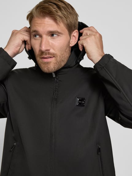 Männermodel trägt Regular Fit Jacke mit Stehkragen von Emporio Armani in Schwarz, Zweiwege-Reißverschluss, Nahaufnahme Oberkörper.