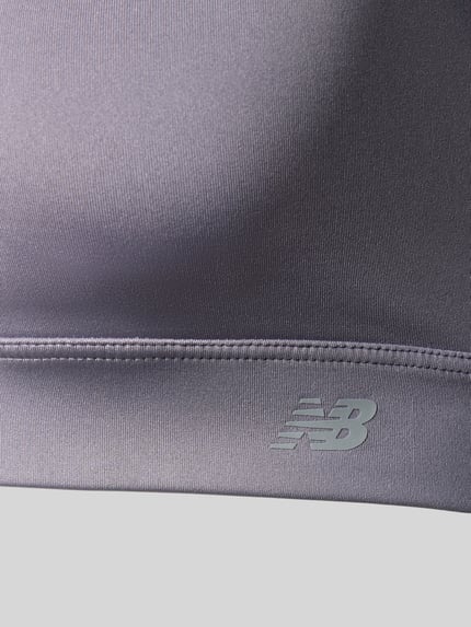 Produktfoto, silbergrauer Yoga BH mit rückseitigem Cut Out von New Balance, glatte Textur, dehnbares Material, Nahaufnahme Oberkörper.