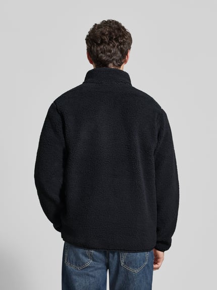 Männermodel trägt Regular Fit Fleecejacke mit Logo-Patch von Columbia, schwarze Fleece-Textur, elastische Abschlüsse, Ganzkörperansicht Rückansicht.