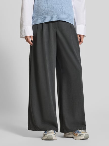 Frauenmodel trägt Weite Hose mit Viskose-Anteil Modell 'STELLA' von VERO MODA in Dunkelgrau, fließender Stoff, Damen Weite Hose, Nahaufnahme Unterkörper.