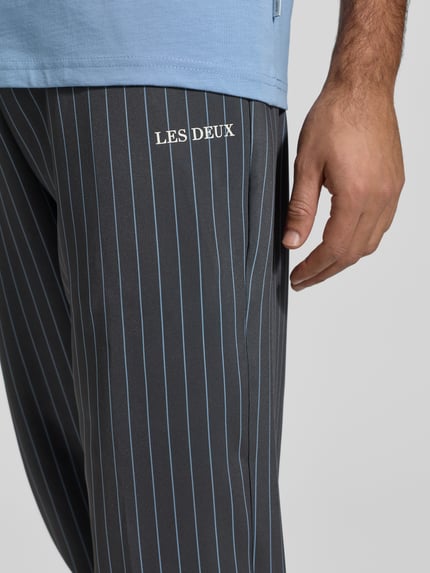 Männermodel trägt Stoffhose mit elastischem Bund Modell 'Ballier' von Les Deux, Material-Mix mit Stretch-Anteil, Label-Print, Nahaufnahme Oberkörper.