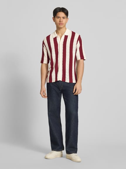 Männermodel trägt Regular Fit Poloshirt mit Knopfleiste Modell 'TYLER' von Jack & Jones, Baumwoll-Mix, gestreift, Ganzkörperansicht von vorne. Rückenlänge bei Größe M: 70 cm, Schulterbreite: 62 cm, Ärmellänge: 30 cm, 1/2-Arm.