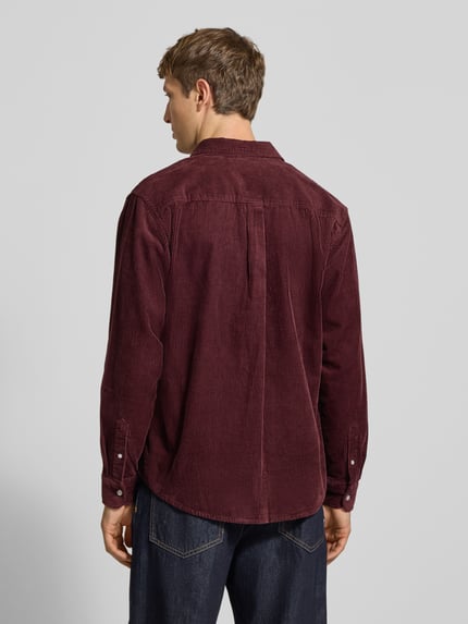 Męski model nosi Regular Fit Freizeithemd mit Logo-Stitching Modell 'MADISON' von Carhartt Work In Progress z bawełny, kołnierzyk typu button down, listwa guzikowa, sportowe mankiety, zaokrąglony dół, bordowy kolor, tekstura sztruksu, widoczna szerokość ramion: 47 cm, długość tyłu: 75 cm, długość rękawów: 65 cm, ujęcie całej sylwetki z tyłu.