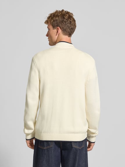 Männermodel trägt Strickjacke mit Reißverschluss Modell 'FREDERIKSBERG' von JACK & JONES, cremefarben mit Kontraststreifen, Ganzkörperansicht Rückansicht, Baumwoll-Mix, Regular Fit, gerippter Stehkragen, Rückenlänge 66 cm, Ärmellänge 74 cm.