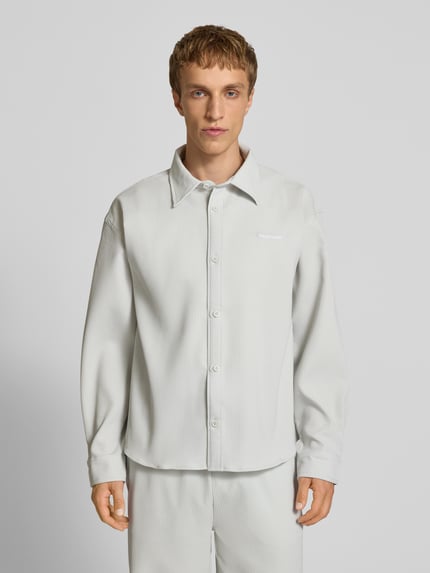 Männermodel trägt Regular Fit Freizeithemd mit Kentkragen und Label-Stitching von Pegador, hellgrau mit feiner Streifenstruktur, Ganzkörperansicht von vorne, Material-Mix mit Stretch-Anteil.