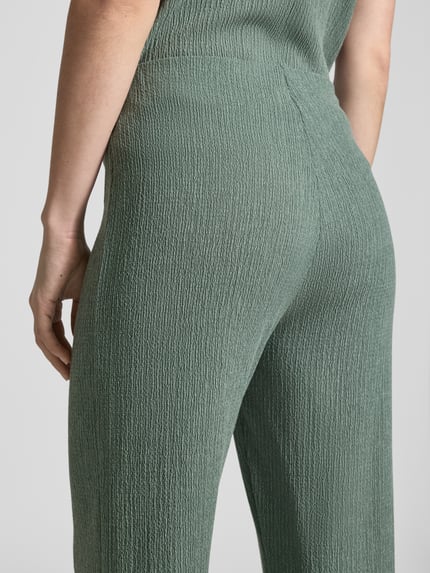Frauenmodel trägt Hose mit Strukturmuster und elastischem Bund von Christian Berg Woman, Material-Mix mit Viskose-Anteil, Relaxed-Fit, dezentes Grün, Nahaufnahme Rückansicht.